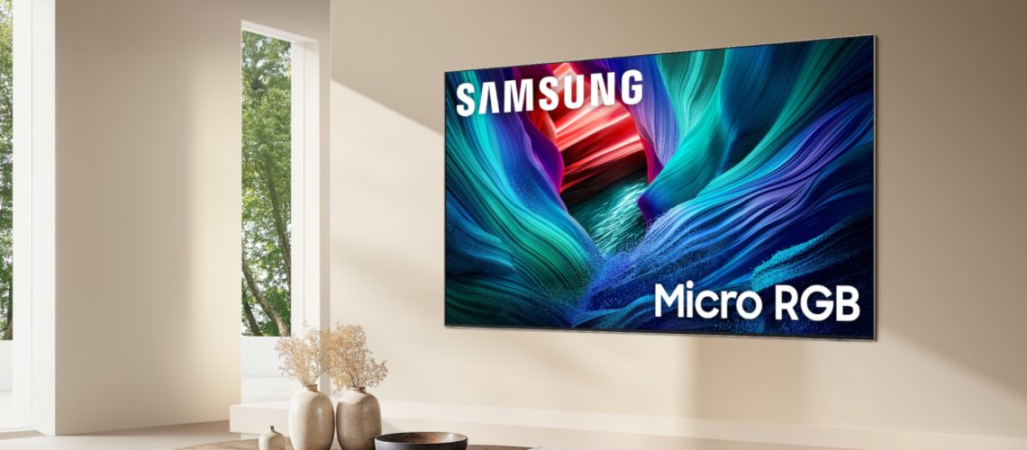 The 115-inch Samsung Micro RGB TV mounted on the wall of a modern, beige-colored living room. On the screen is an abstract, multicolored image alongside the following words: "Samsung Micro RGB."