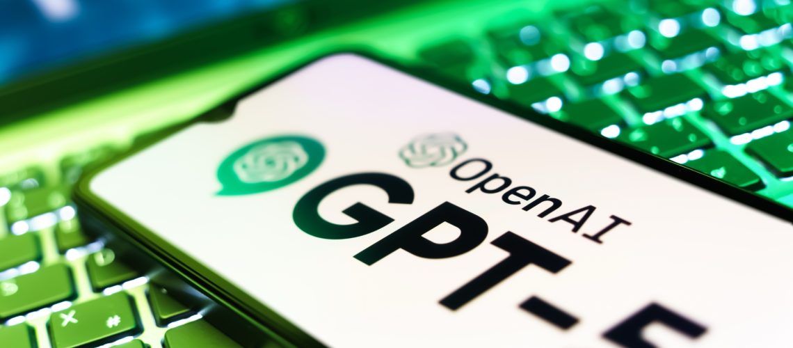 ChatGPT-5 logo on phone resting on laptop keyboard
