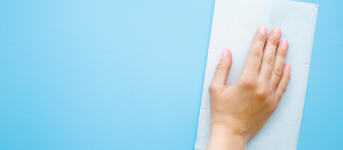 A woman's hand wiping a blue wall