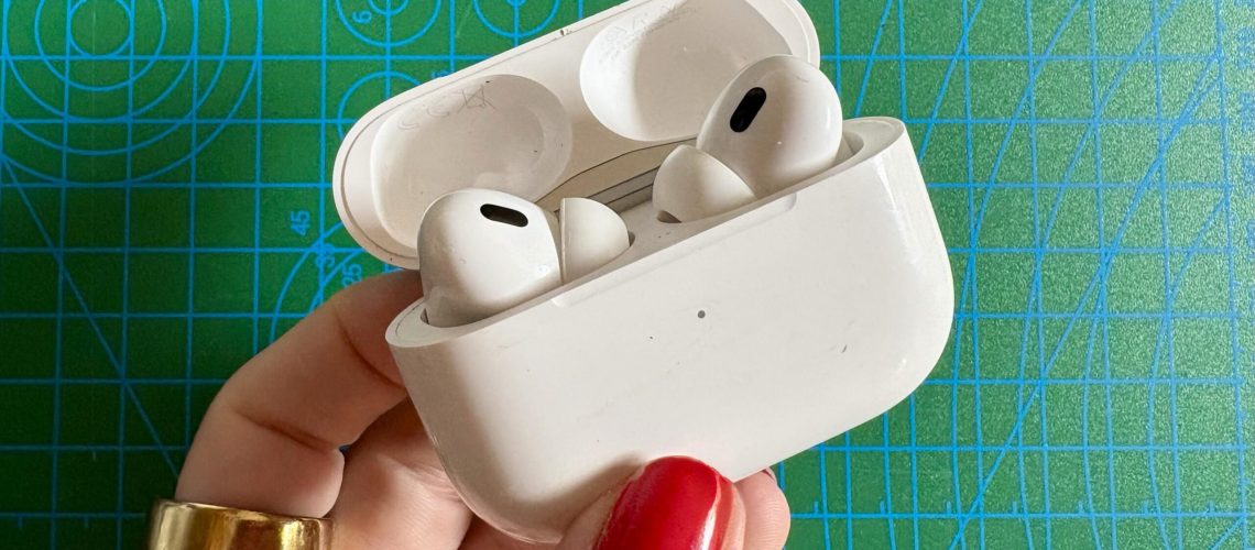 Person holding the Apple AirPods Pro 2 in front of a green background