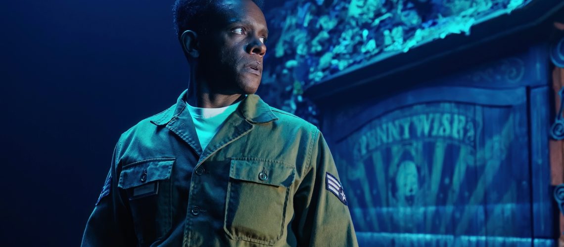 A first-look photo from "IT: Welcome to Derry" featuring actor Chris Chalk with a "Pennywise" circus display board behind him