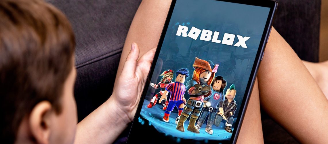 A boy playing Roblox on a table on the couch