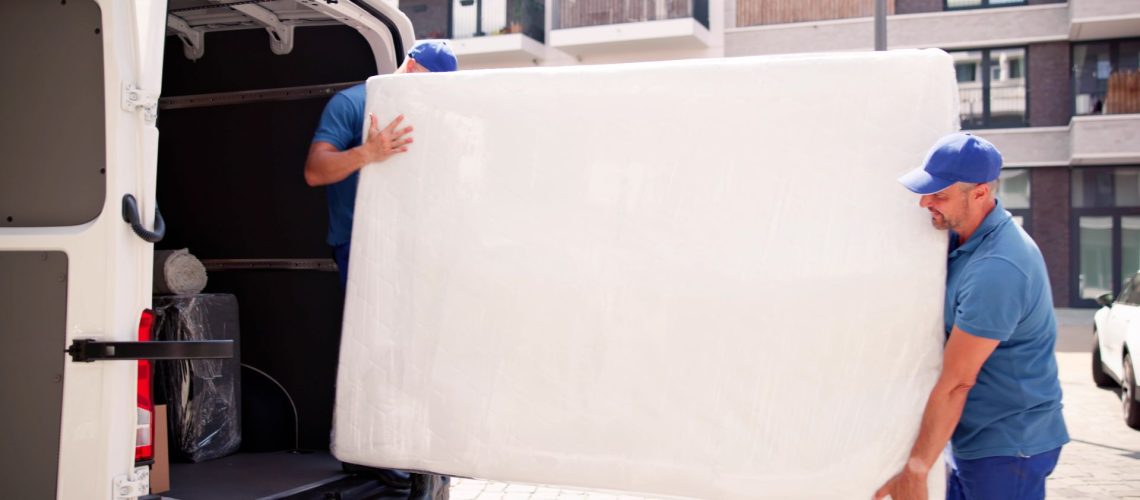 Two movers moving a mattress into a van
