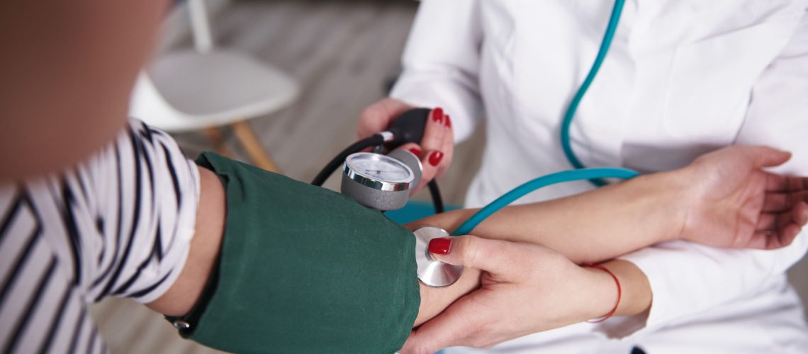 Doctor taking a patient's blood pressure at an appointment