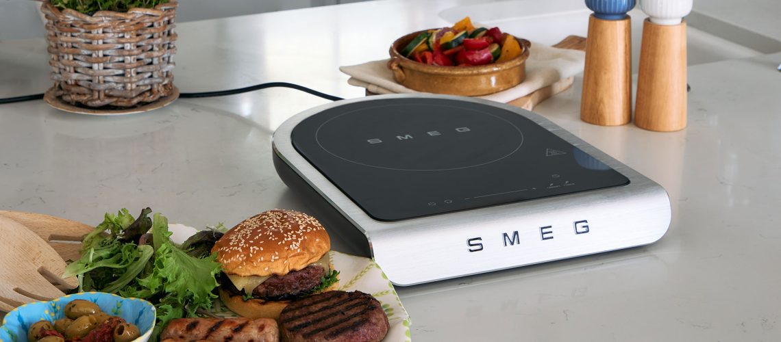 Smeg portable induction cooktop with a range of cooked food to the side