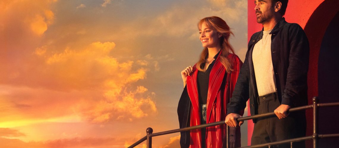 L-R: Margot Robbie and Colin Farrell stand looking out at a sunset in a promotional still for "A Big Bold Beautiful Journey"