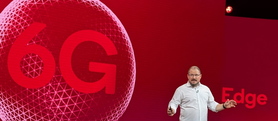 Qualcomm CEO Cristiano Amon on stage with 6G graphic concept behind him