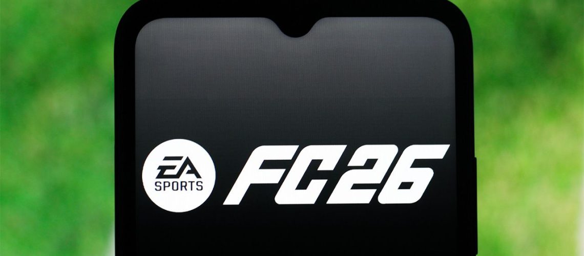 EA FC 26 logo displayed on a smartphone with the grass of a football pitch in the background