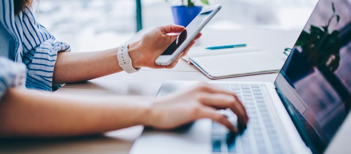 Woman using smartphone and laptop