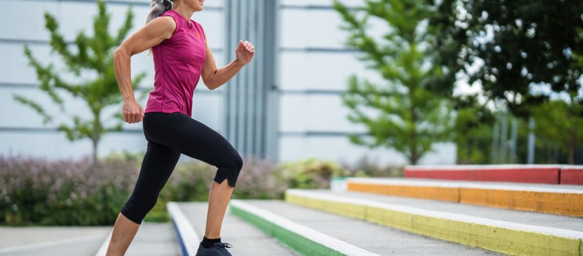 Older woman in activewear power walking up stairs outdoors