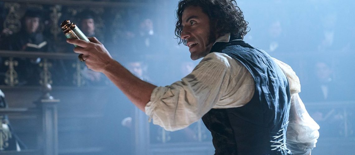 Promotional image from Guillermo del Toro's Frankenstein featuring Oscar Isaac holding an object up to a room full of observers.