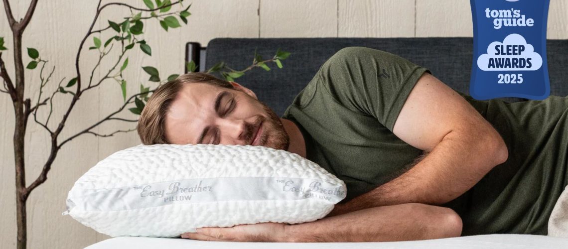 A man wearing a green t shirt lying on his side with his head resting on the Nest Bedding Easy Breather Side Sleeper Pillow