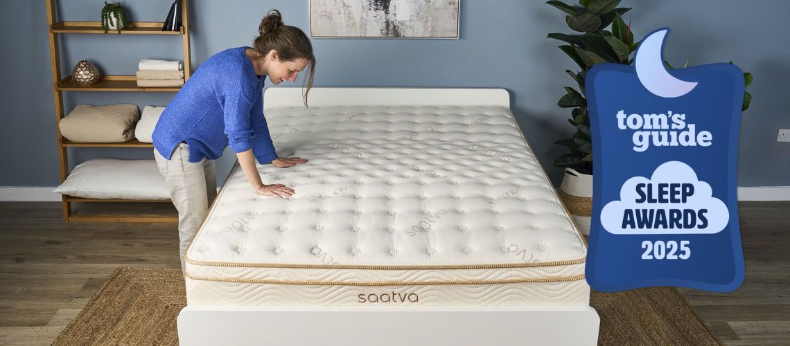 A Saatva Classic mattress in a bedroom, with a woman pressing her hands down on it and a Tom's Guide Sleep Awards 2025 badge overlaid