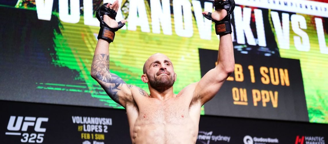 Alexander Volkanovski raises his arms to the air in the final press conference before fighting Diego Lopes in their rematch for the UFC Featherweight Championship.