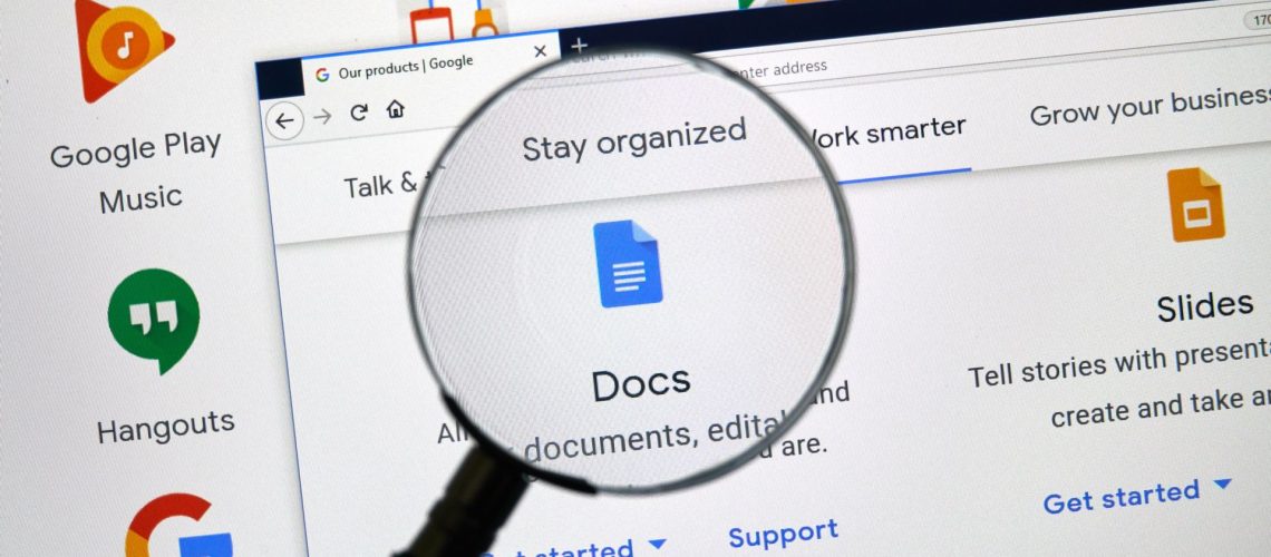 A magnifying glass over the Google Docs logo on a computer screen, representing an article about how to change cases on Google Docs