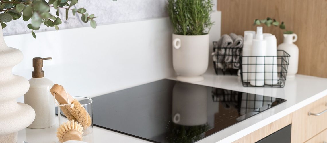 Induction cooktop in a white kitchen next to natural cleaning products