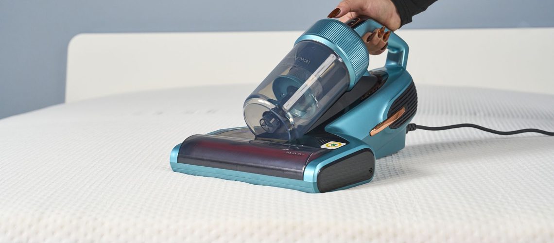 A close up of a hand holding the Jimmy Mattress Vacuum Cleaner and using it to clean the surface of a mattress
