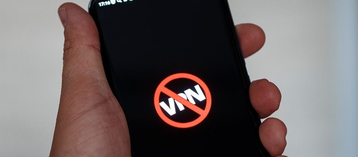 Person holding smartphone with VPN lettering crossed out