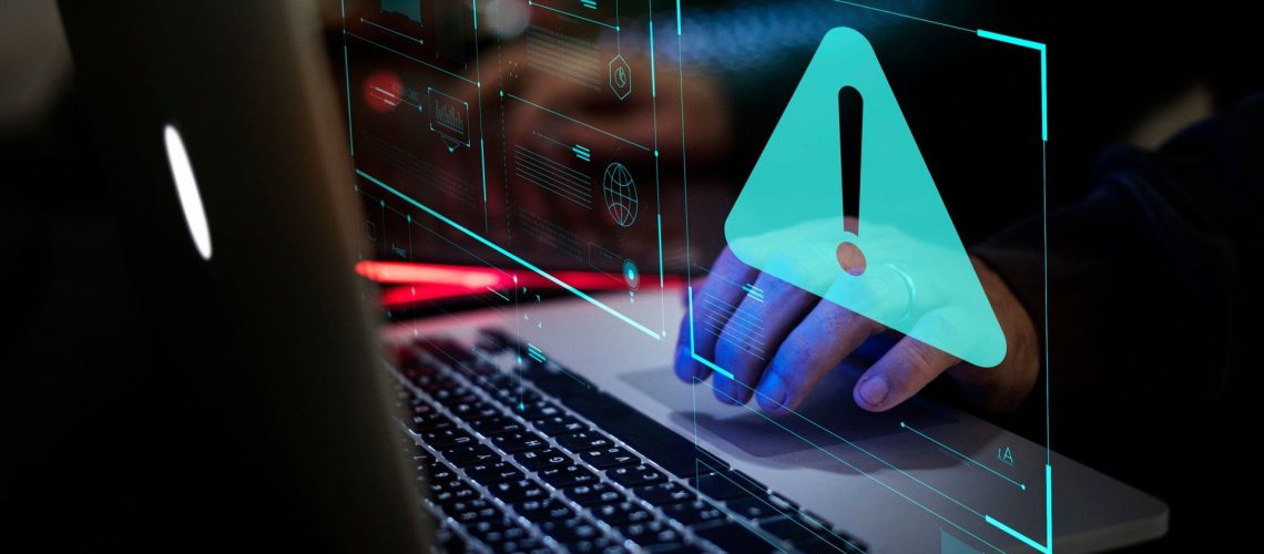 A person using a laptop with a warning message appearing on screen