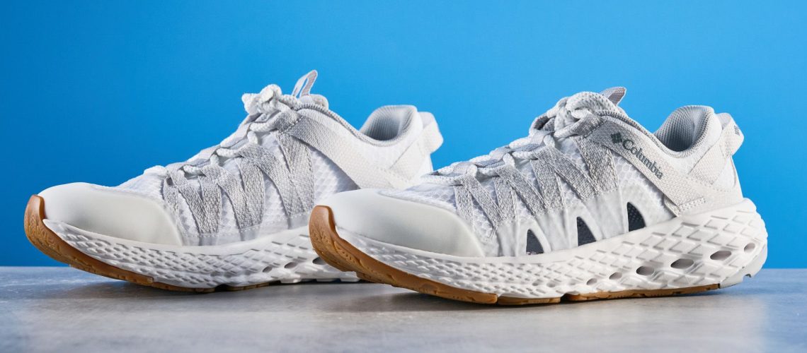 Columbia Drainmaker shoes in white photographed in front of a blue background.