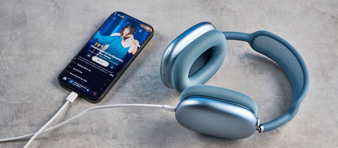 the apple airpods max 2 in blue photographed against a blue tom's guide background, showing the mesh headband, anodized aluminum ear cups, carry case, and controls