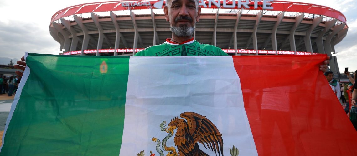 A fan shows a flag of Mexico outside the Estadio Azteca.