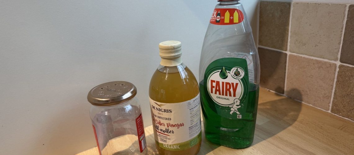 Apple cider vinegar, dish soap and a mason jar on a countertop