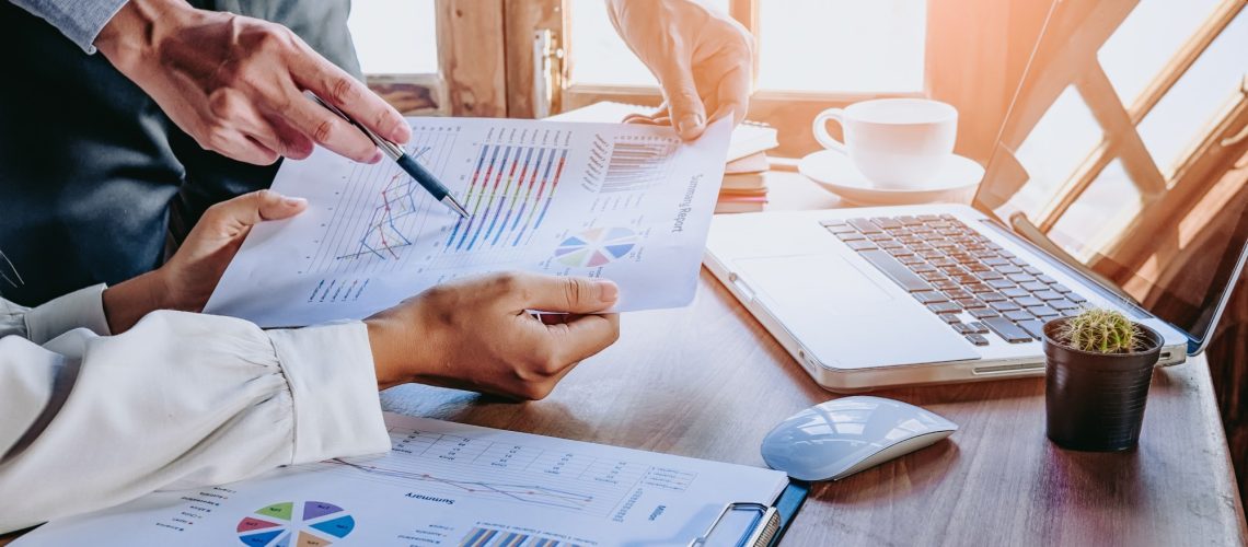 Business team analyzing income charts and graphs with modern laptop computer