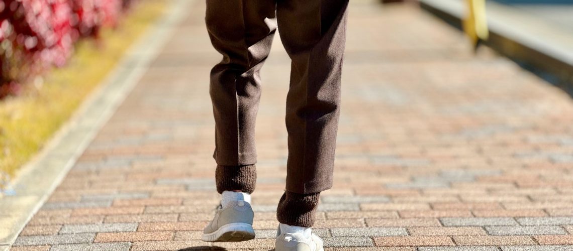 The feet of an elderly woman walking on the sidewalk