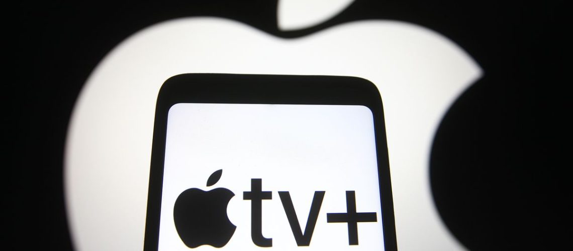 The Apple logo in white glows behind a phone with the Apple TV+ logo on it