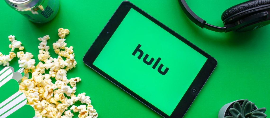 A tablet with the Hulu logo surrounded by popcorn, soda, headphones and a cactus