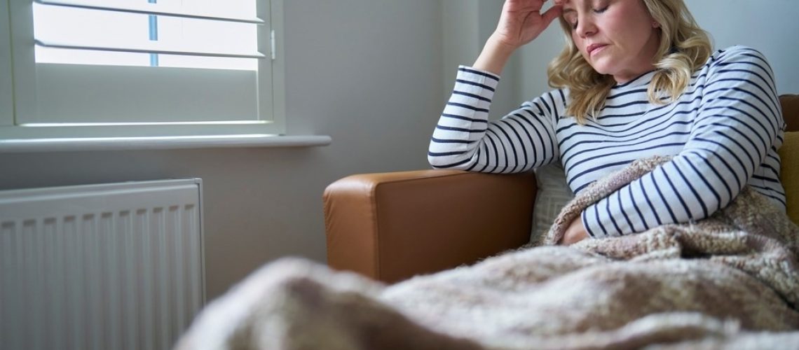 Woman Suffering With Long Term Illness Sitting On Sofa At Home