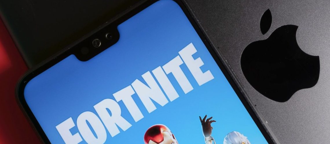 Fortnite running on phone on top of MacBook showing Apple logo