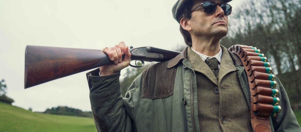 Lord Tony Baddingham (David Tennant) poses with a shotgun over his shoulder in "Rivals"