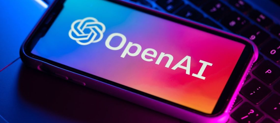 OpenAI logo on phone sitting on top of laptop keyboard
