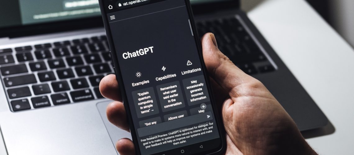 ChatGPT running on phone with laptop in the background