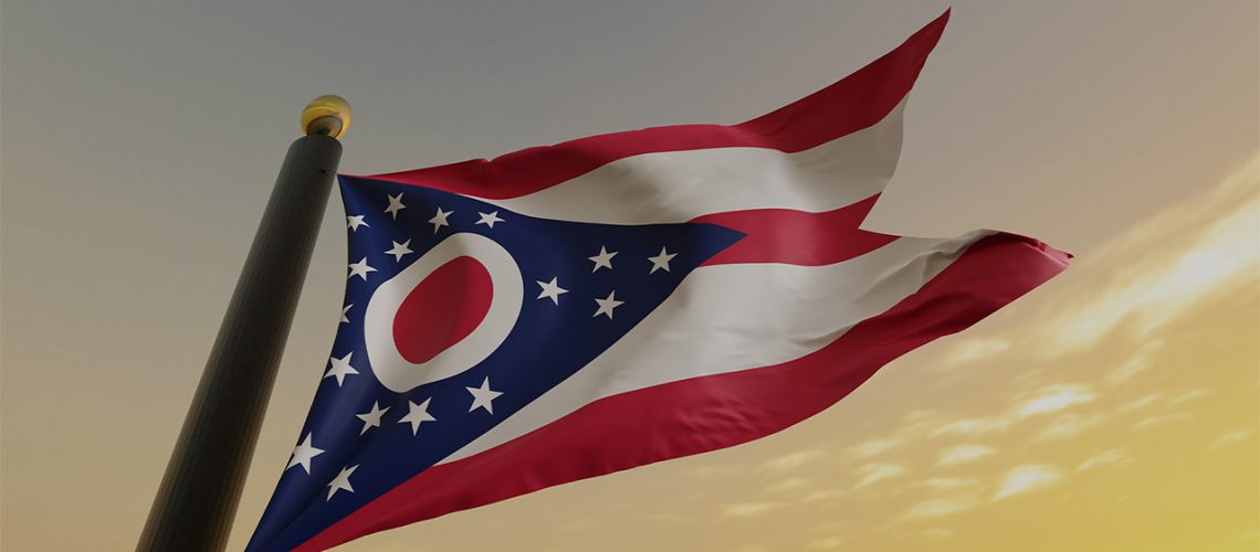 Red, white, and blue flag of Ohio flying at dusk
