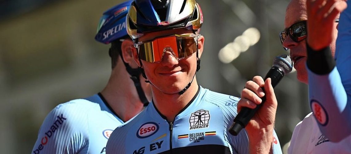 Remco Evenepoel, wearing a helmet, smiles before a cycling race.