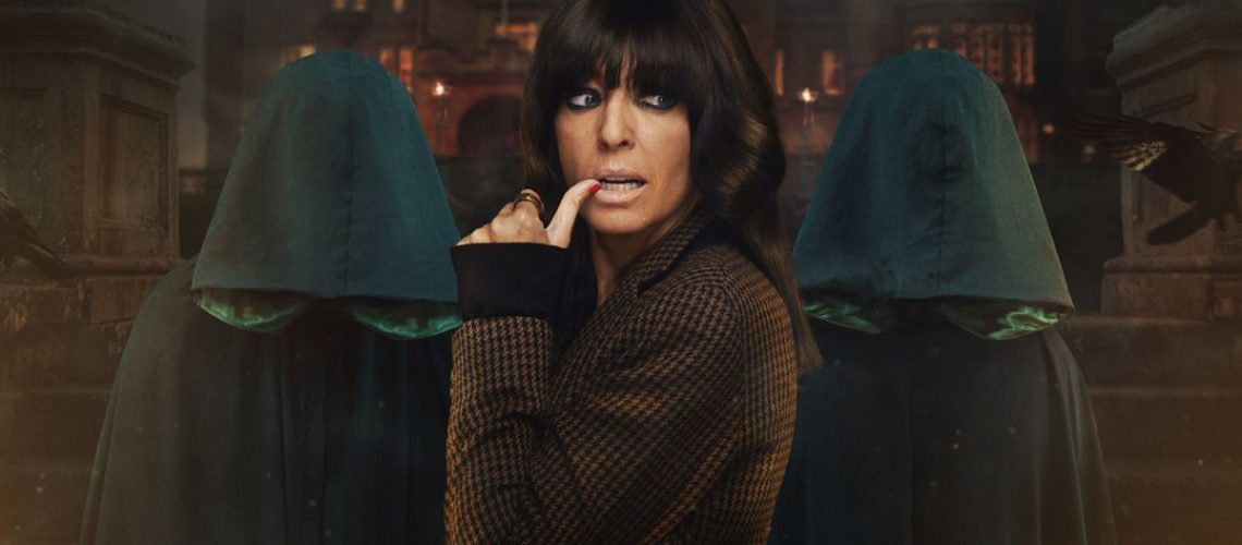 Claudia Winkleman posing in front of two hooded figures to promote The Traitors season 2