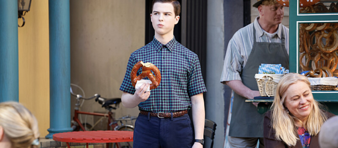 Sheldon Cooper (Iain Armitage) eating a pretzel outside a German cafe in