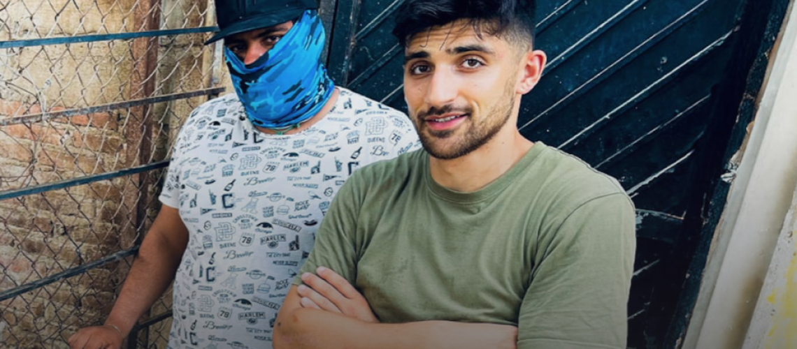 Documentary-maker Ben Zand poses next to an electric fence with a sinister-looking member of the Sinaloa Cartel in a face mask.