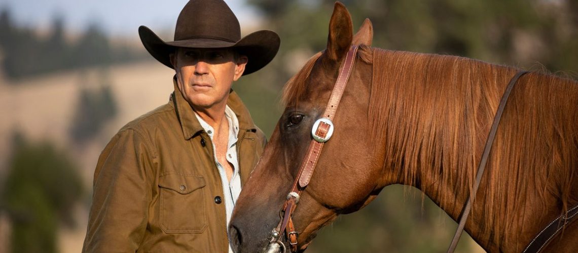 Kevin Costner as John Dutton, next to a horse, in