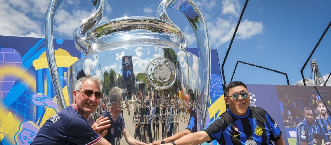 An Inter and a PSG fan posing with a giant trophy ahead of the 2025 Champions League final in Munich, Germany on May 29, 2025.