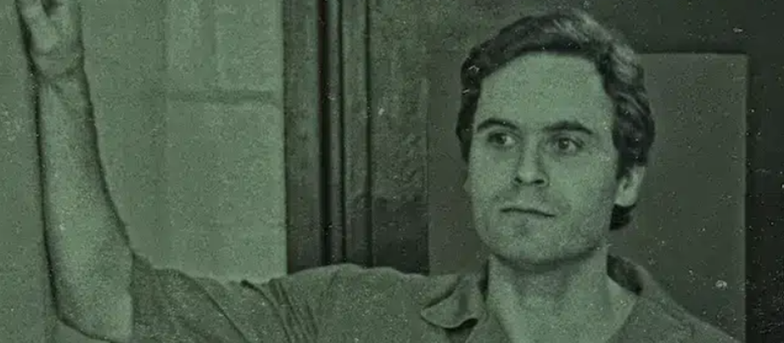 Ted Bundy leaning on a wall in a prison jumpsuit