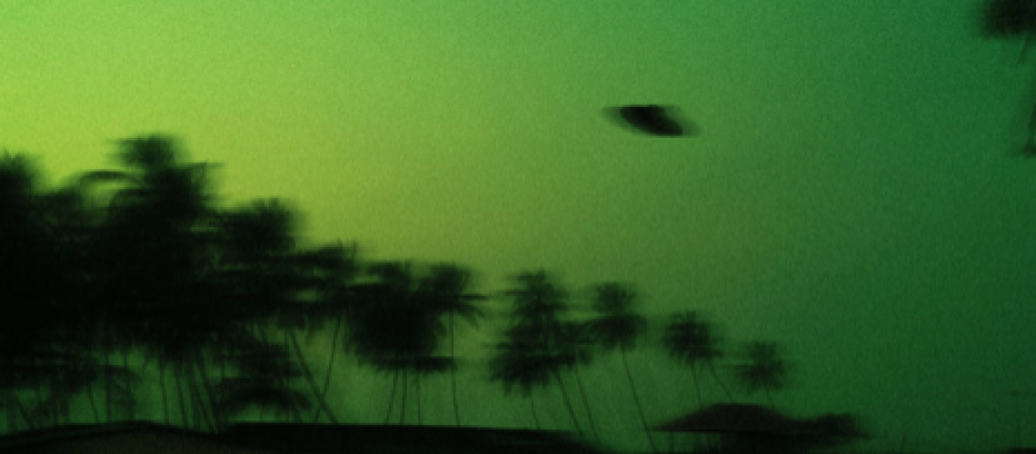 A blurred image appears to show the silhouette of a UFO flying over some trees