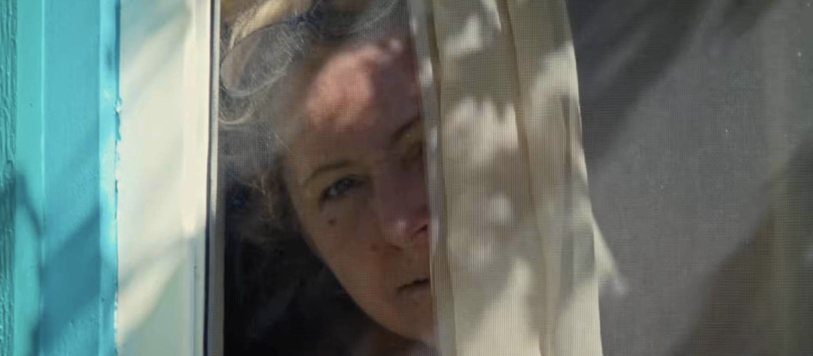 Old woman looking out from behind curtain