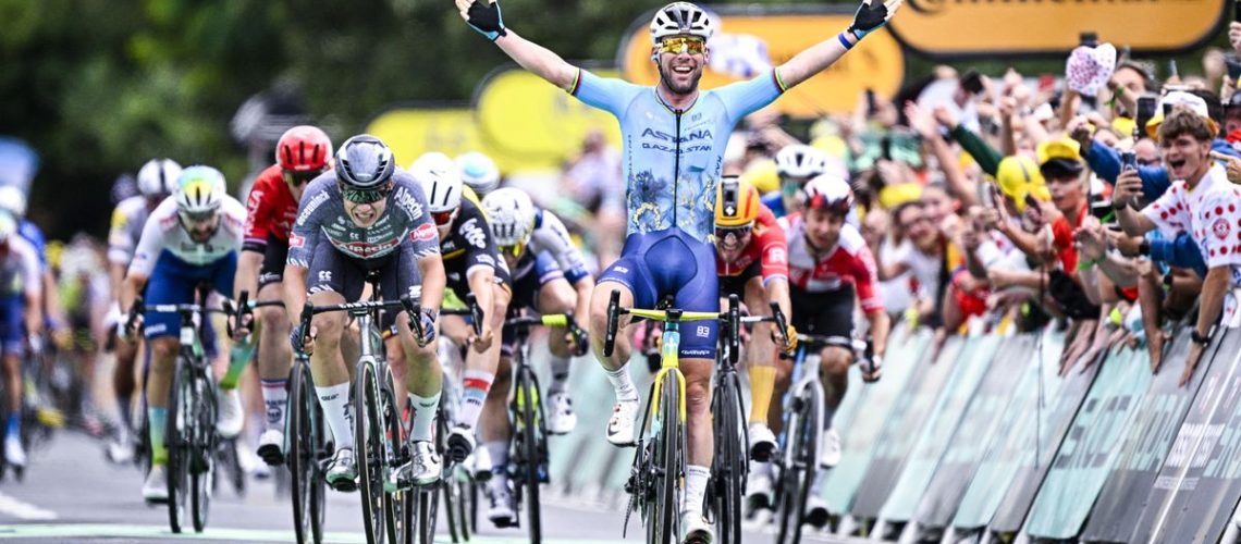 Mark Cavendish, in Astana Qazaqstan blue, crosses the line in first at the 2024 Tour de France.