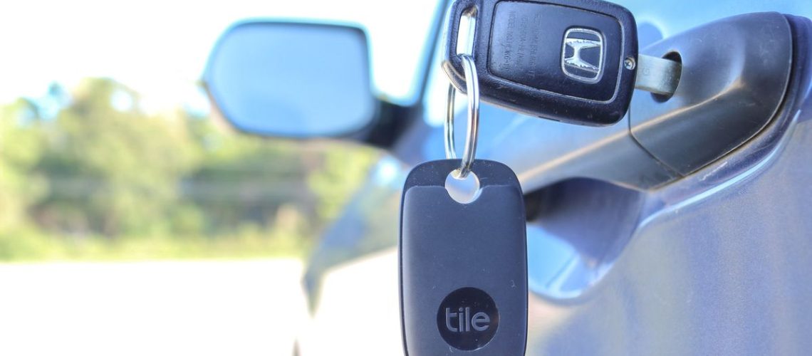 A Tile Pro Bluetooth key finder on a set of keys in a car door
