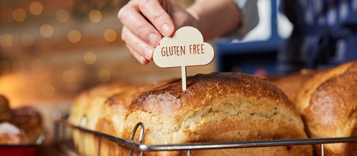 Sales Assistant In Bakery Putting Gluten Free Label Into Freshly Baked Bread
