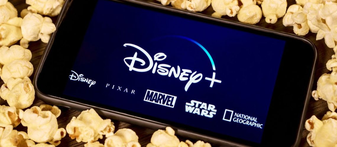 The Disney Plus logo on a phone surrounded by popcorn
